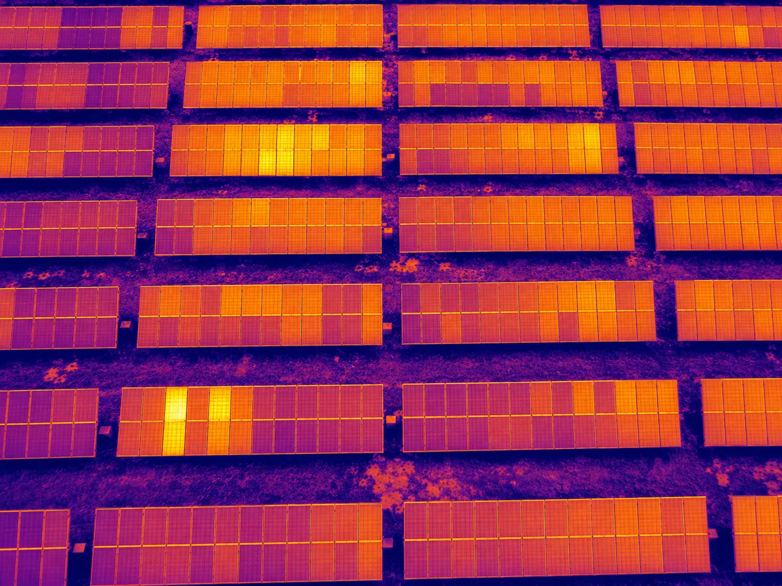 Thermal-palette aerial view of solar module rows; restrained and technically plausible.