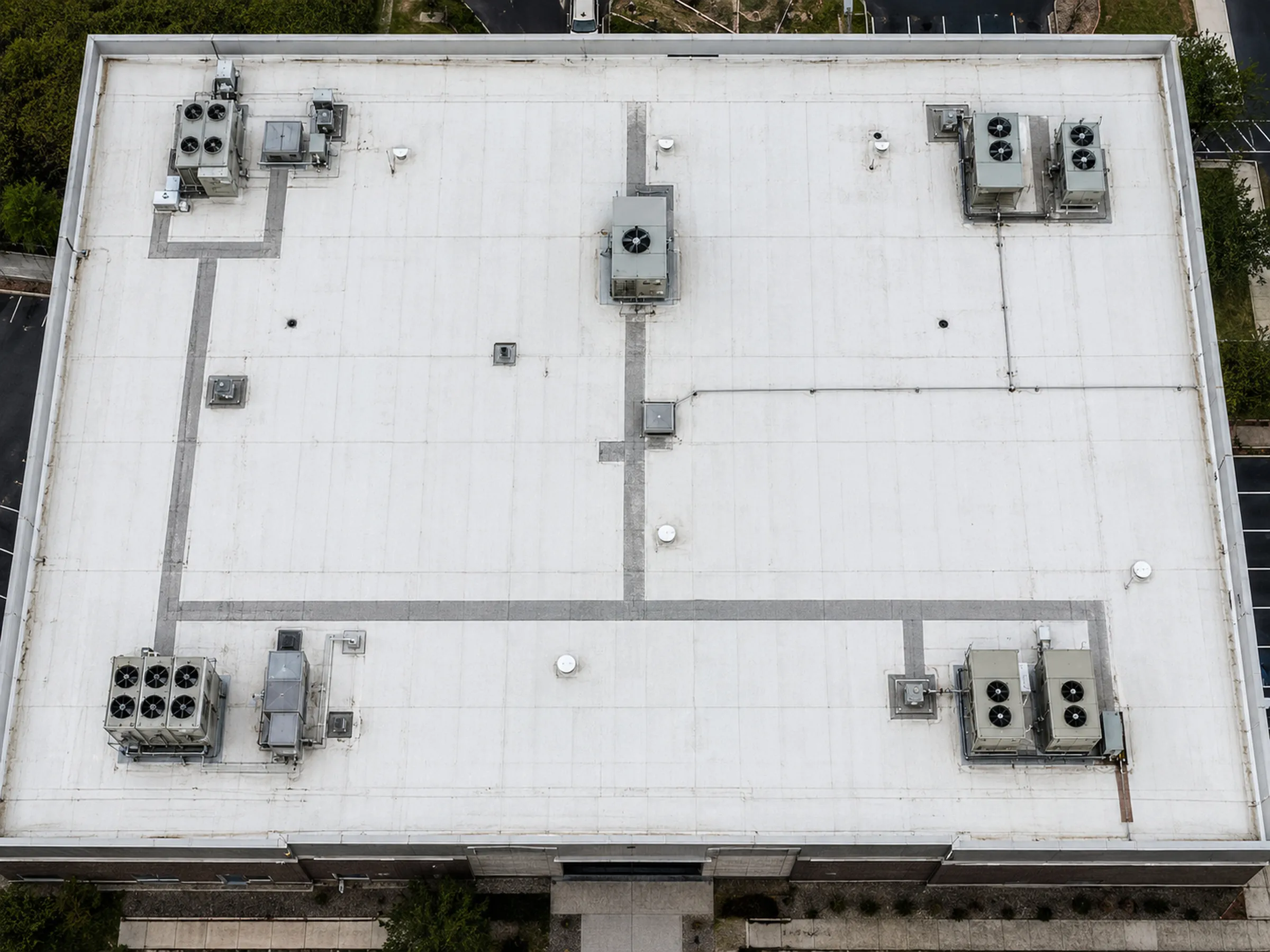 Commercial rooftop with mechanical equipment and drainage detail, viewed from directly above or a steep oblique.