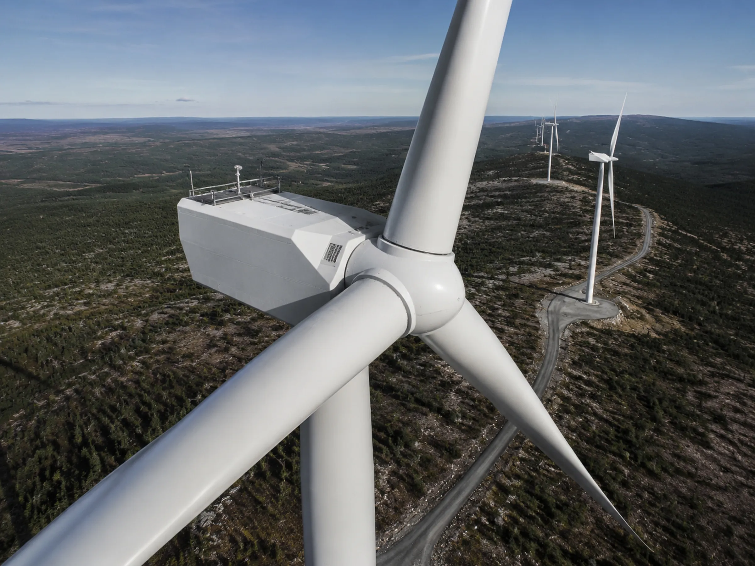 Wind turbines and associated infrastructure in an operating landscape; the turbine is the subject, not the aircraft.